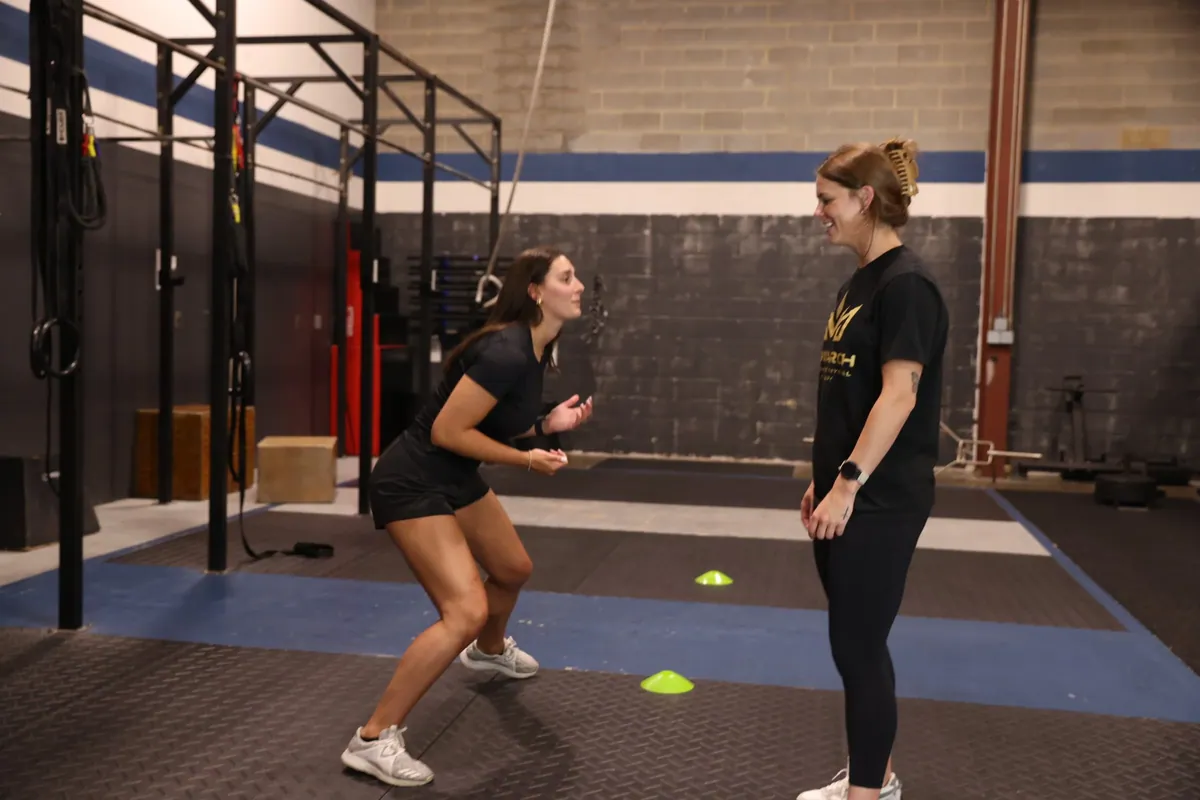 An athlete shuffles between cones while Kiley Robb, PT, DPT, watches her movement