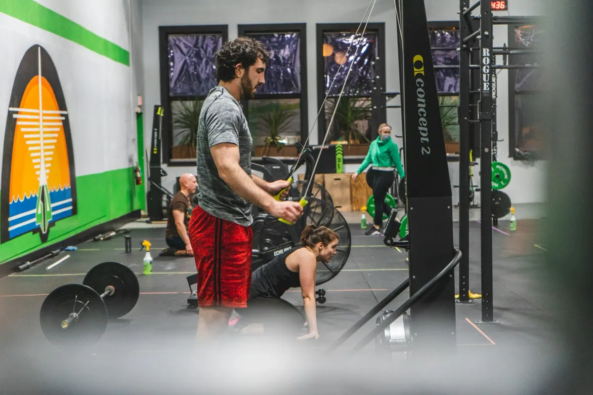 Athletes train with barbells and cable machines in a functional fitness gym
