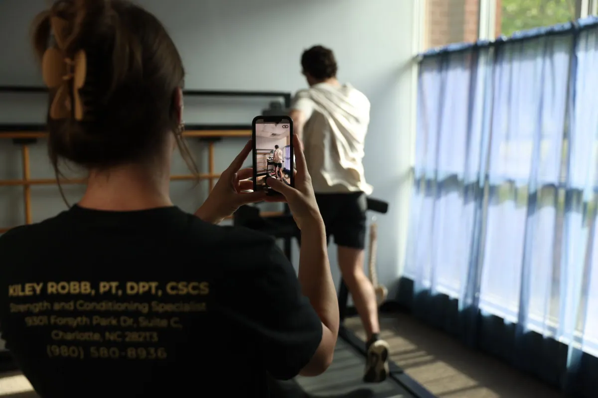 Kiley Robb, PT, DPT, films a runner on a treadmill with her phone for a running analysis