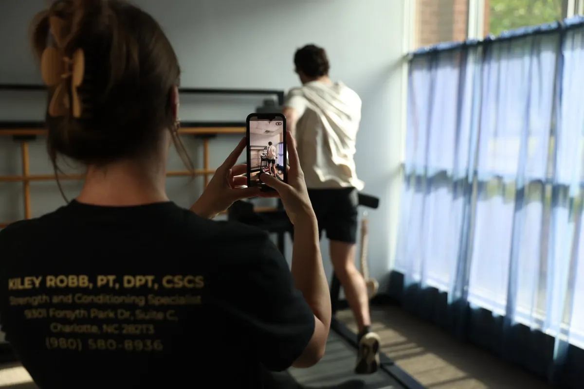 Kiley Robb, PT, DPT, films a runner on a treadmill with her phone for a running analysis