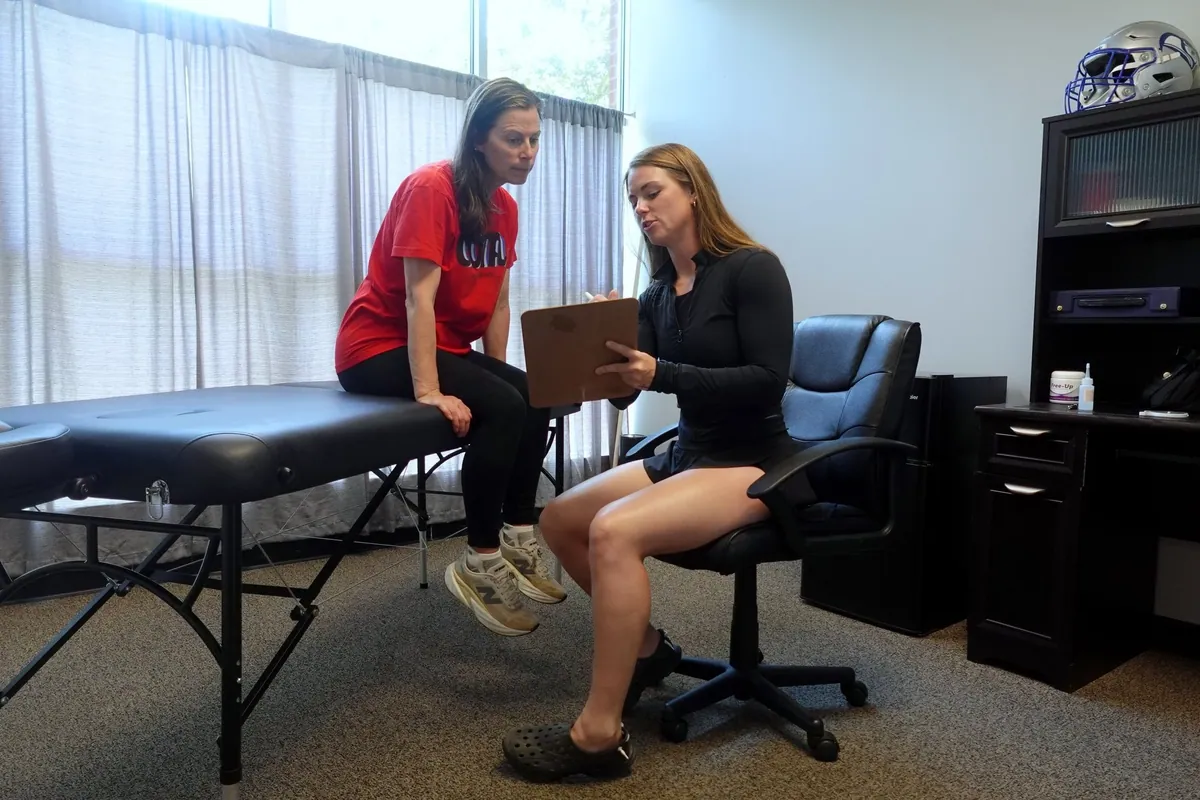 Kiley Robb, PT, DPT, talks through a rehab plan with a patient who sits on a treatment table
